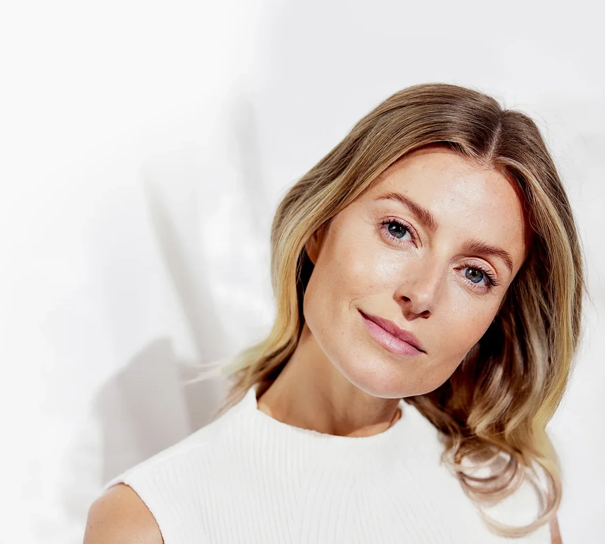 Blond woman in profile tucks hair behind one ear